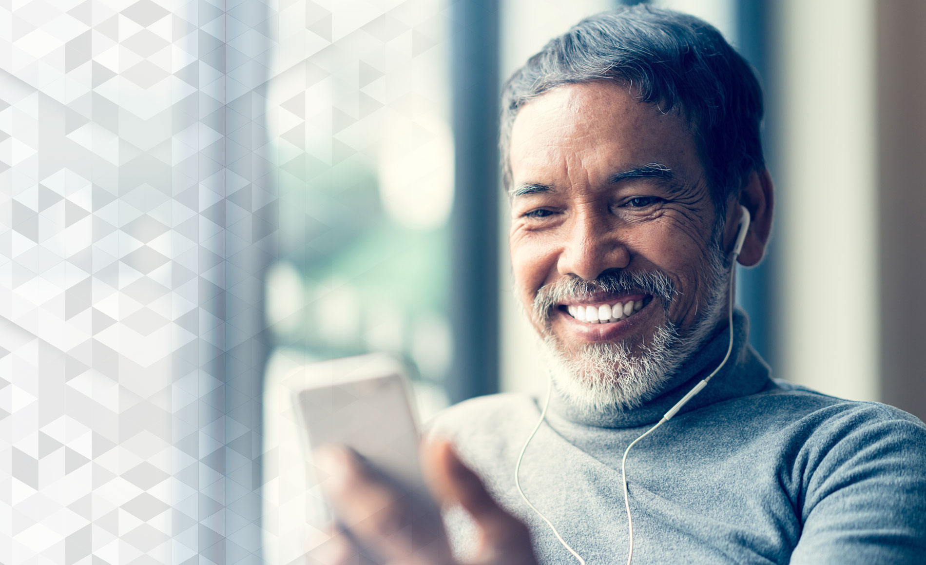 A smiling man showing off his dentures on implants to a friend on his mobile phone